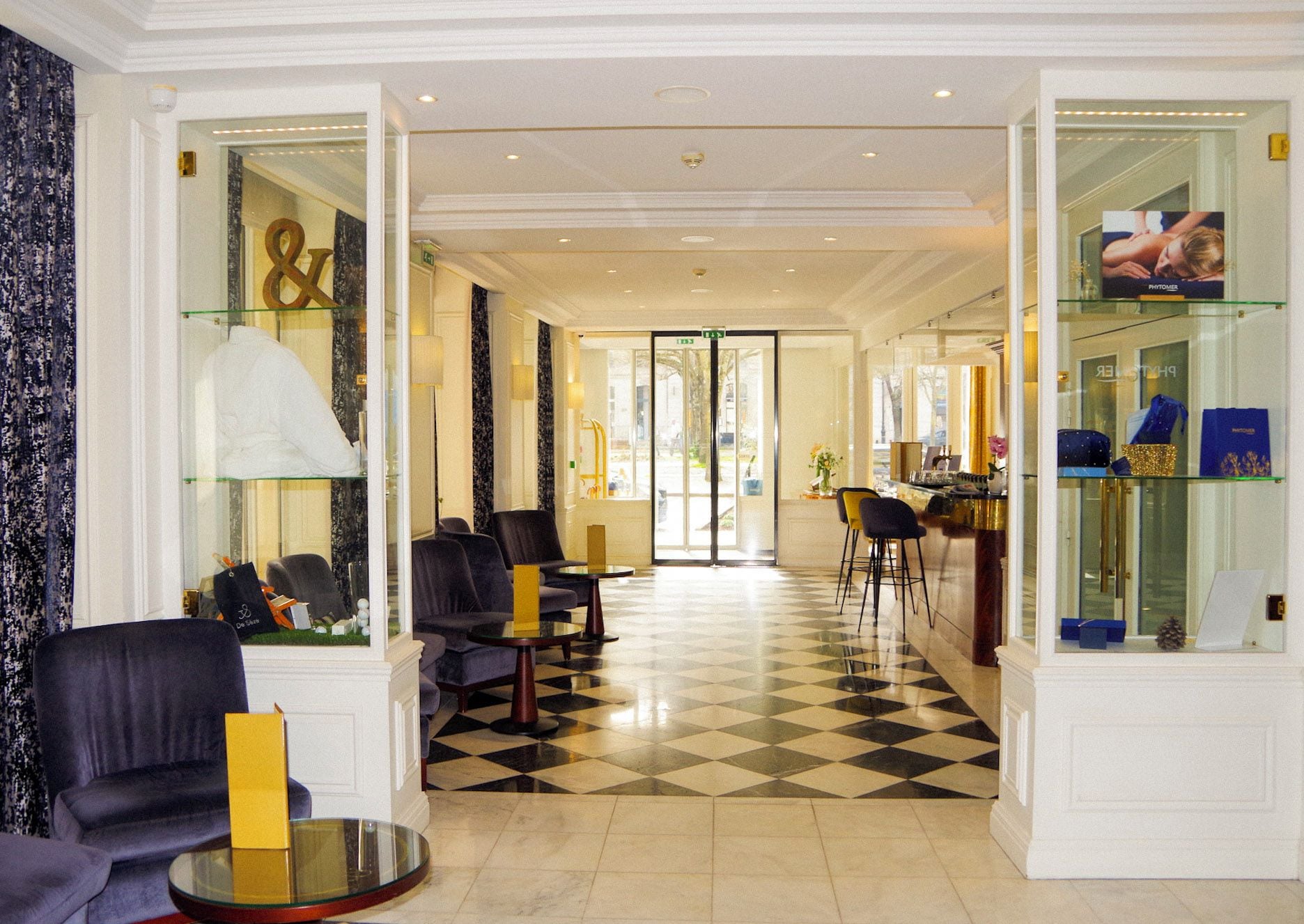 A hotel lobby with a checkered floor, seating areas, and glass display cases.