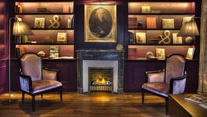 A library with bookshelves, a fireplace, and two armchairs. - Hôtel de Sèze (Bordeaux)