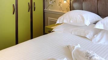 Une chambre d’hôtel avec un lit, des oreillers blancs et une armoire verte.