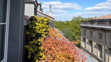 Un bâtiment à la façade grise, doté d’une cheminée visible et d’un balcon orné de feuillage d’automne.