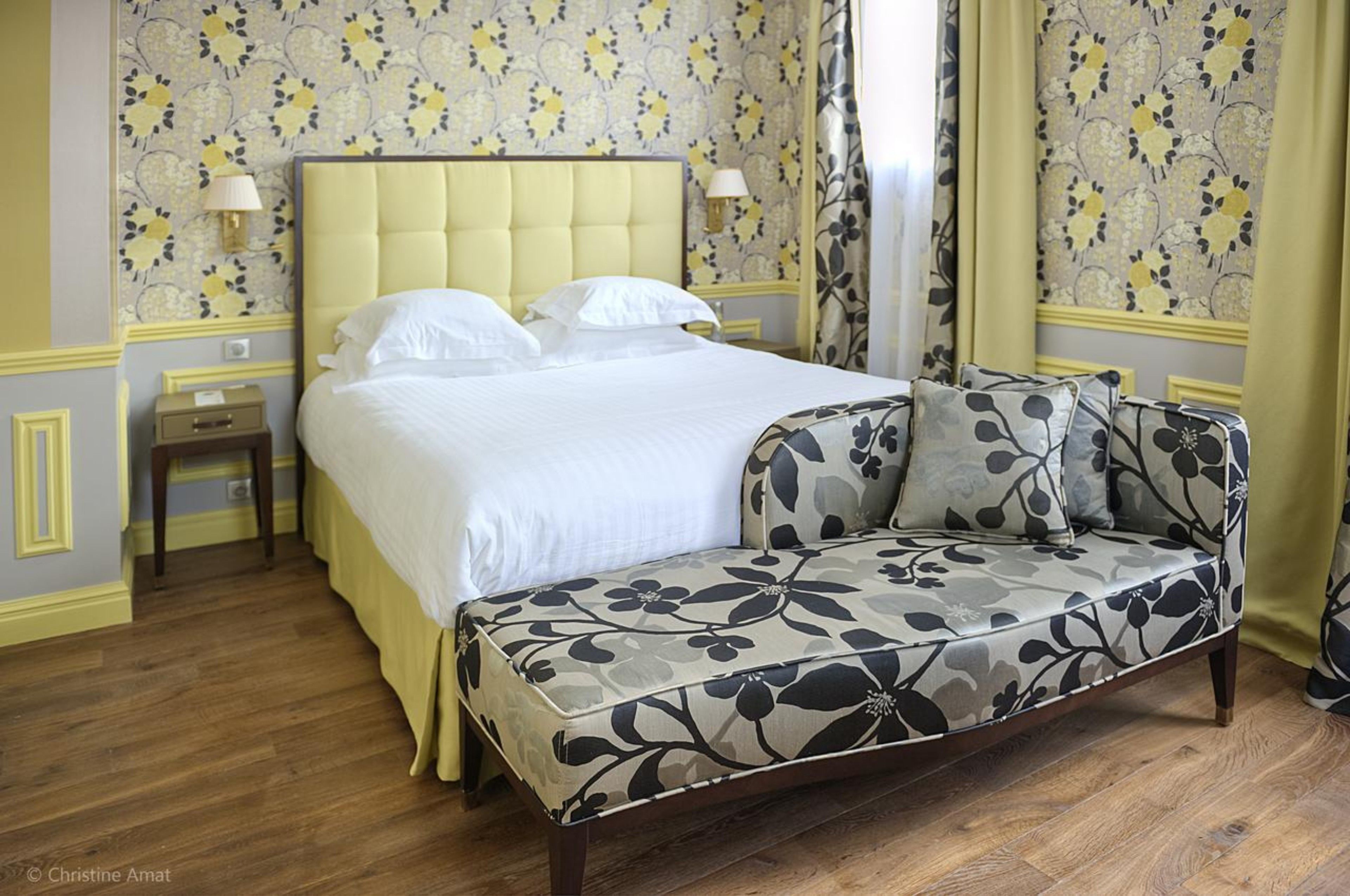 A bedroom with a bed, a sofa, a nightstand, and a lamp.