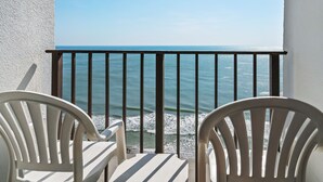 A balcony with a view of the sea, featuring two white chairs and a table. - Palace Resort (Myrtle Beach)