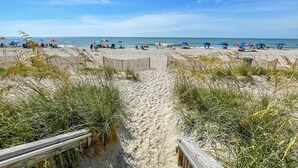 A beach with a wooden boardwalk leading to the sand, surrounded by tall grass. - Palace Resort (Myrtle Beach)