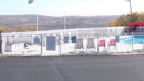 A fenced pool area with signs indicating pool hours and no diving.