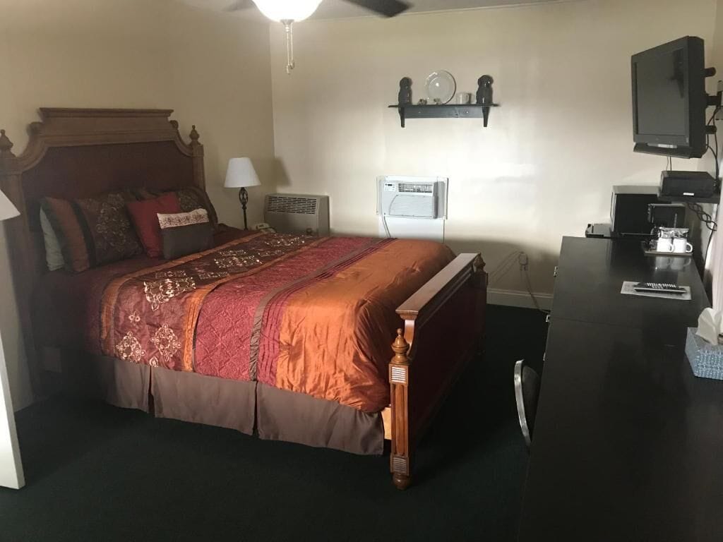 Un dormitorio con cama, mesita de noche, lámpara, equipo de aire acondicionado y televisión.