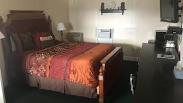 Un dormitorio con cama, mesita de noche, lámpara, equipo de aire acondicionado y televisión.