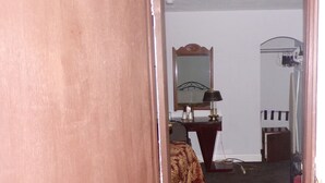 A room with a bed, a desk, a mirror, and a red chair.