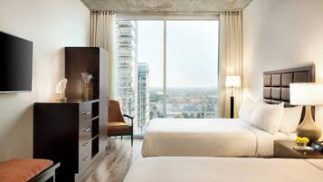 Habitación de hotel con una cama grande, un escritorio, una silla, un televisor y vistas de la ciudad.