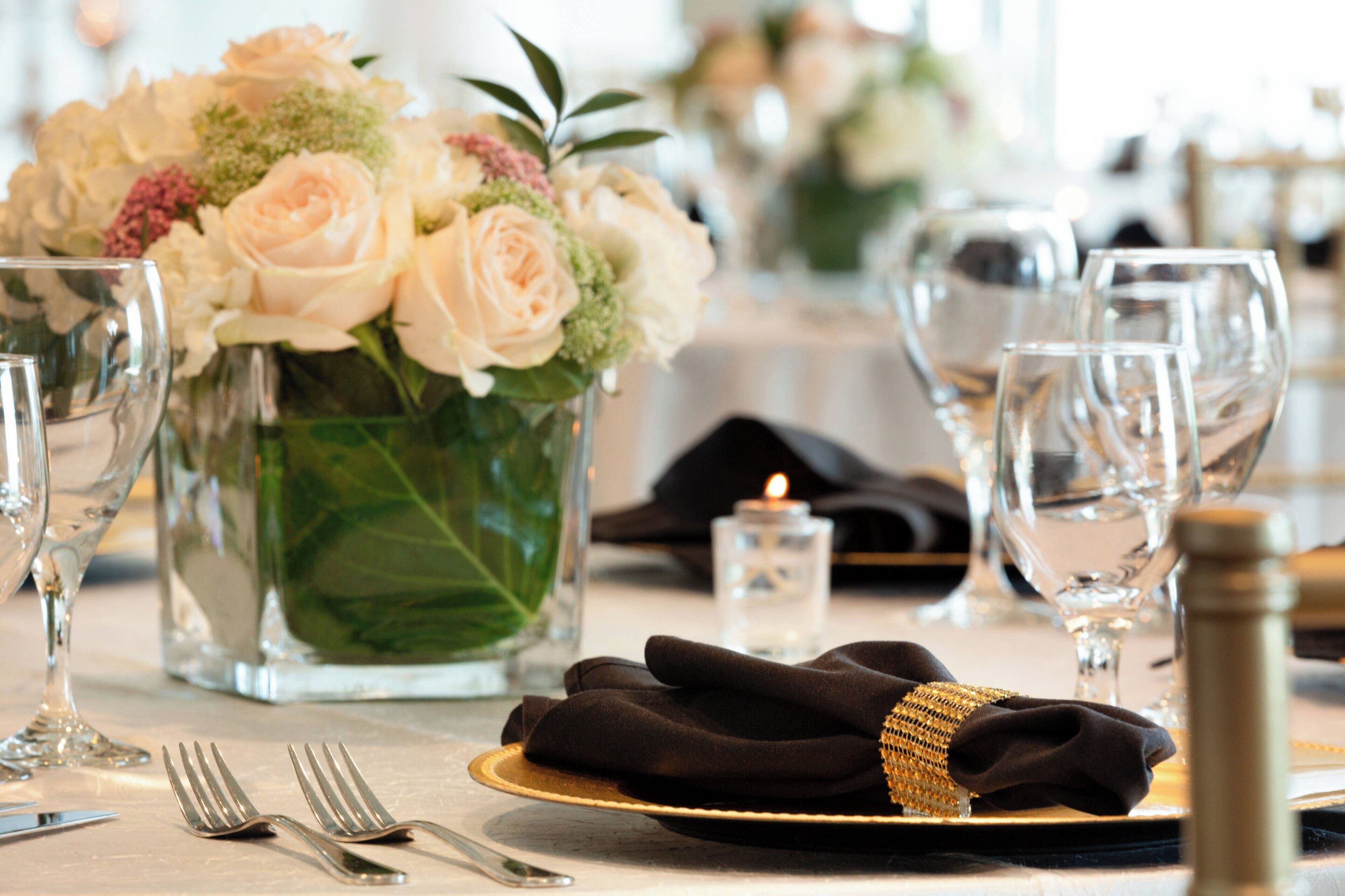 A table set with a vase of flowers, wine glasses, and cutlery.