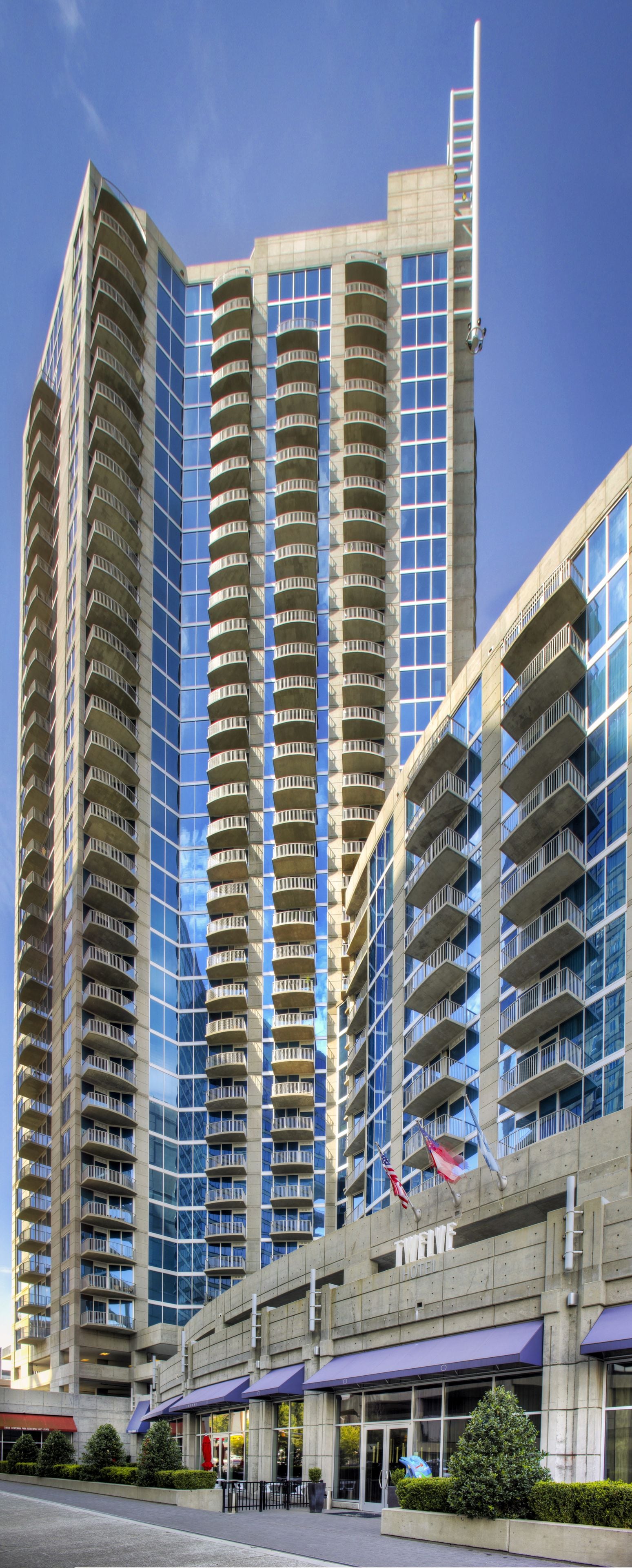 A high-rise hotel with multiple balconies, a prominent entrance with awnings, and flags displayed.