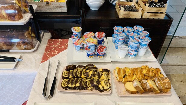 Una mesa de buffet con diversos alimentos, como pasteles, panes y vasos de yogur.