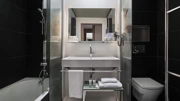 Un baño moderno con ducha envuelta en vidrio, un lavamanos blanco y un inodoro.