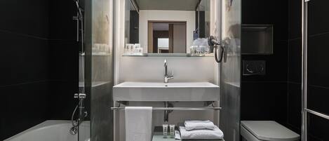 A modern bathroom with a glass-enclosed shower, a white sink, and a toilet.