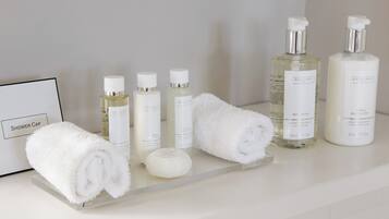 A bathroom vanity with toiletries including a shower cap, towels, and bottles of liquid soap and lotion.