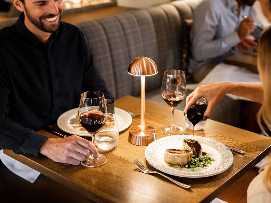 Una mesa de comedor con platos de comida, copas de vino y una vela.
