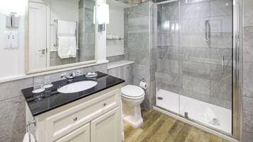Een moderne badkamer met een douchecabine van glas, een wit toilet en een wastafel met een zwart aanrecht.