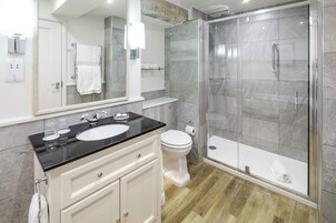 A modern bathroom with a glass-enclosed shower, a white toilet, and a vanity with a black countertop.
