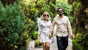 Um casal caminhando por um caminho de pedra, cercado por vegetação exuberante.