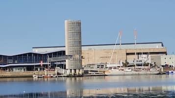 A waterfront building with a modern design, featuring a large cylindrical structure and a flat roof.