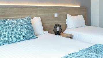 A hotel room with two beds, a nightstand with a lamp, and a wall-mounted picture.