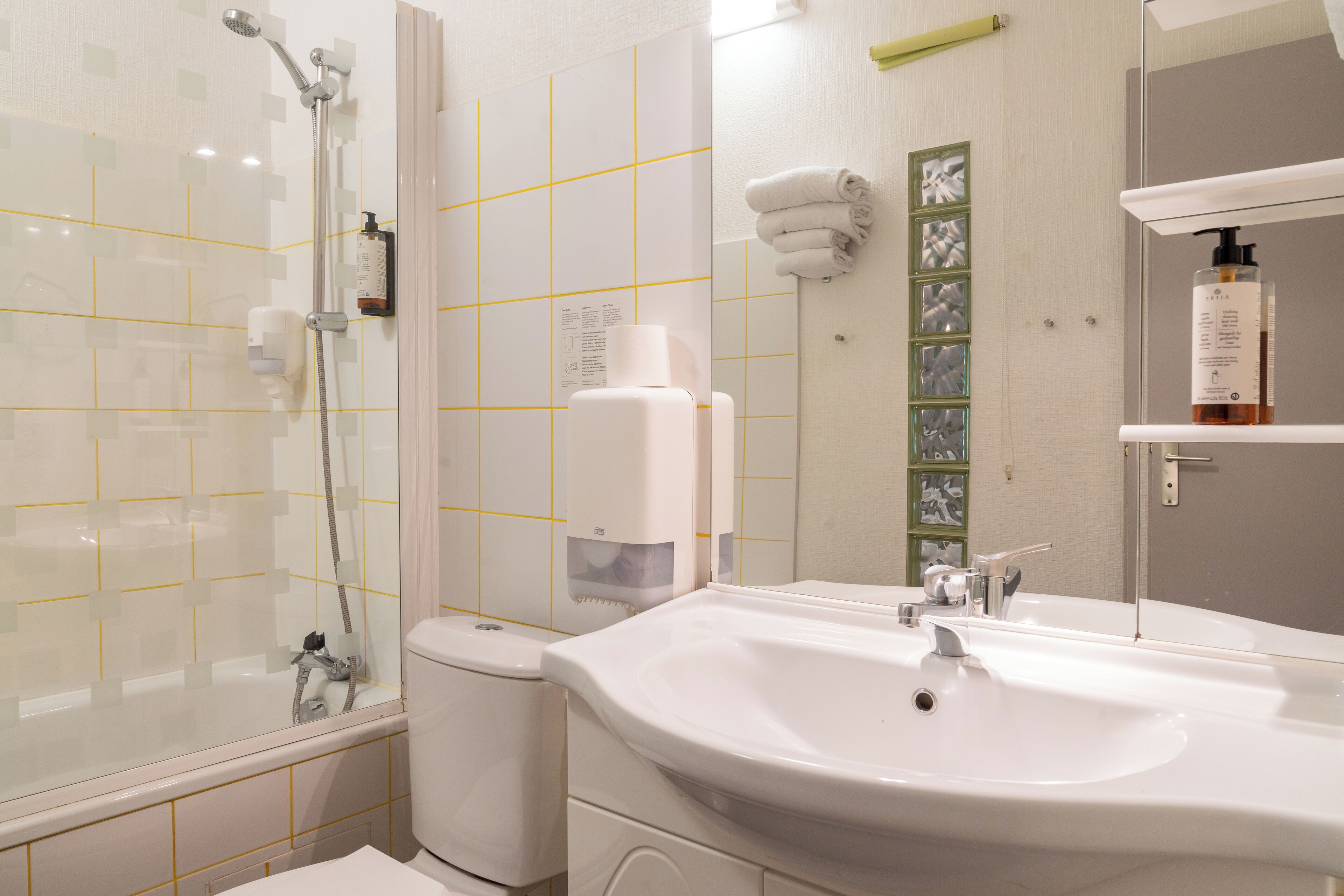 A bathroom with a glass-enclosed shower, a white sink, and a mirror.