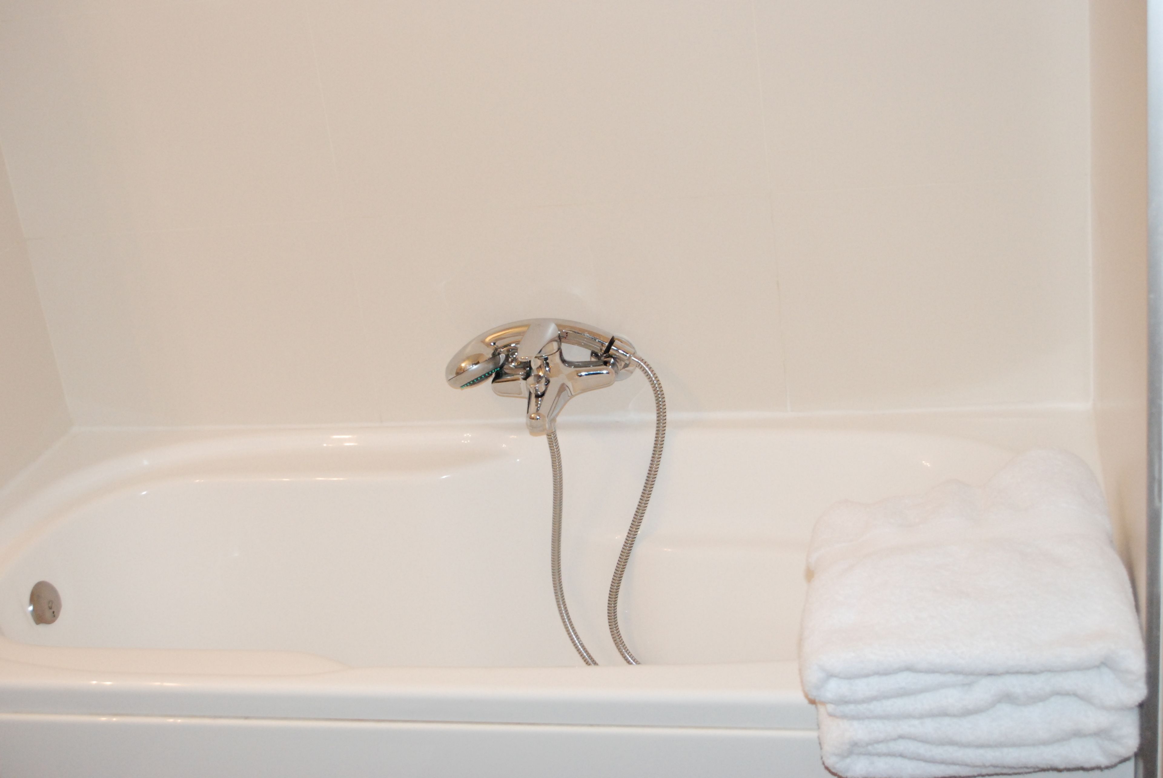 A white bathtub with a shower head and a towel.