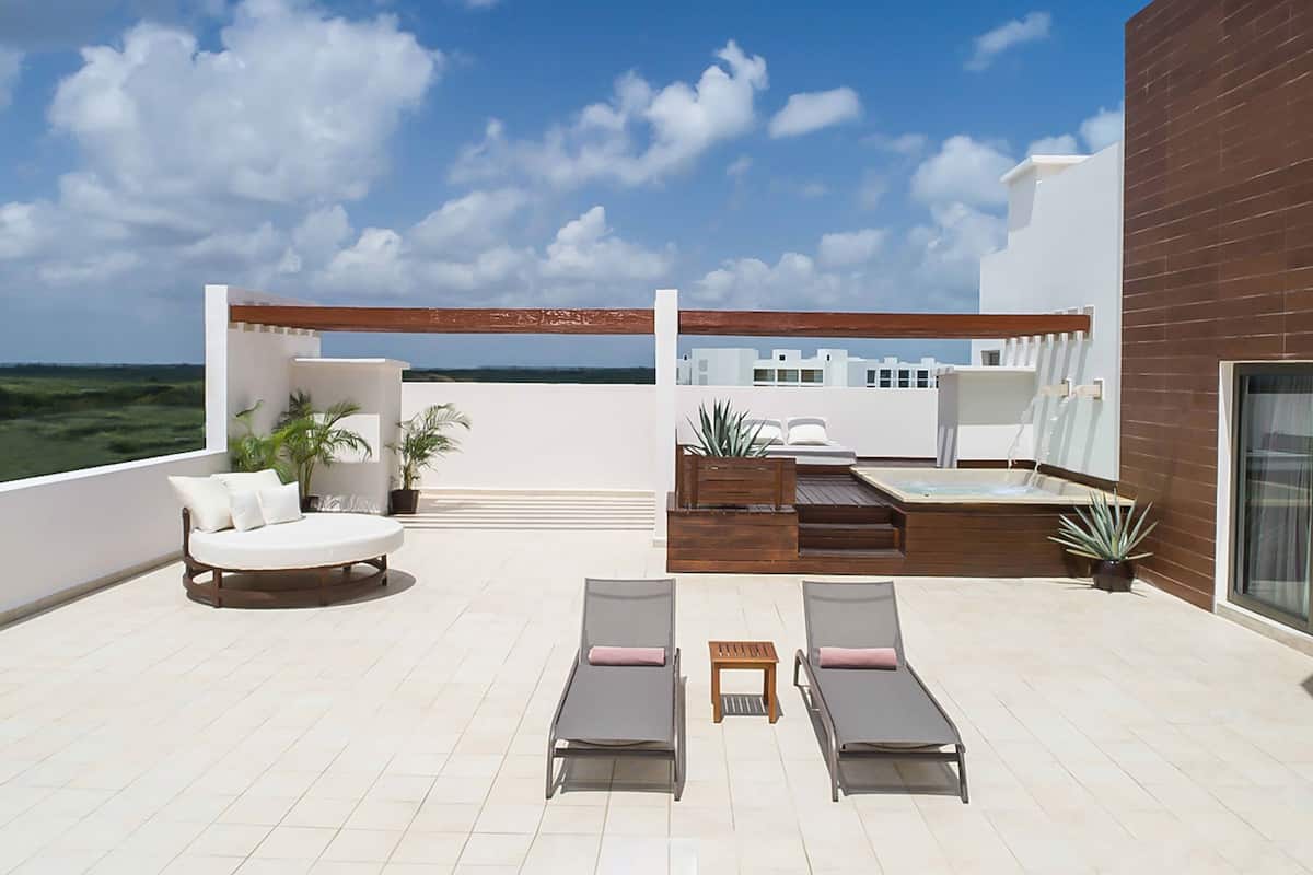 A rooftop terrace with a pool, lounge chairs, and a seating area with a view of the city skyline.