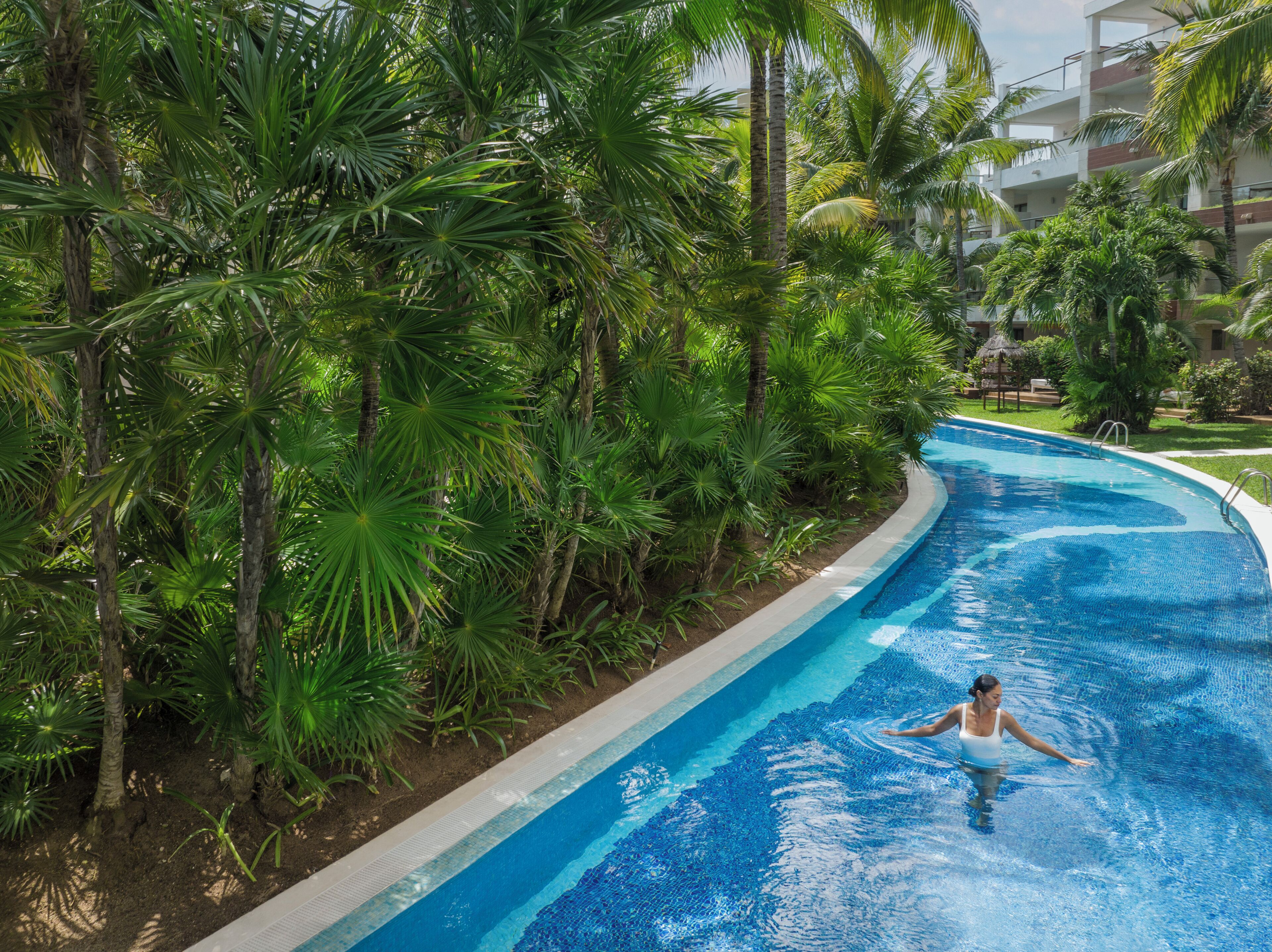 Una piscina rodeada de exuberante vegetación, con una persona nadando.