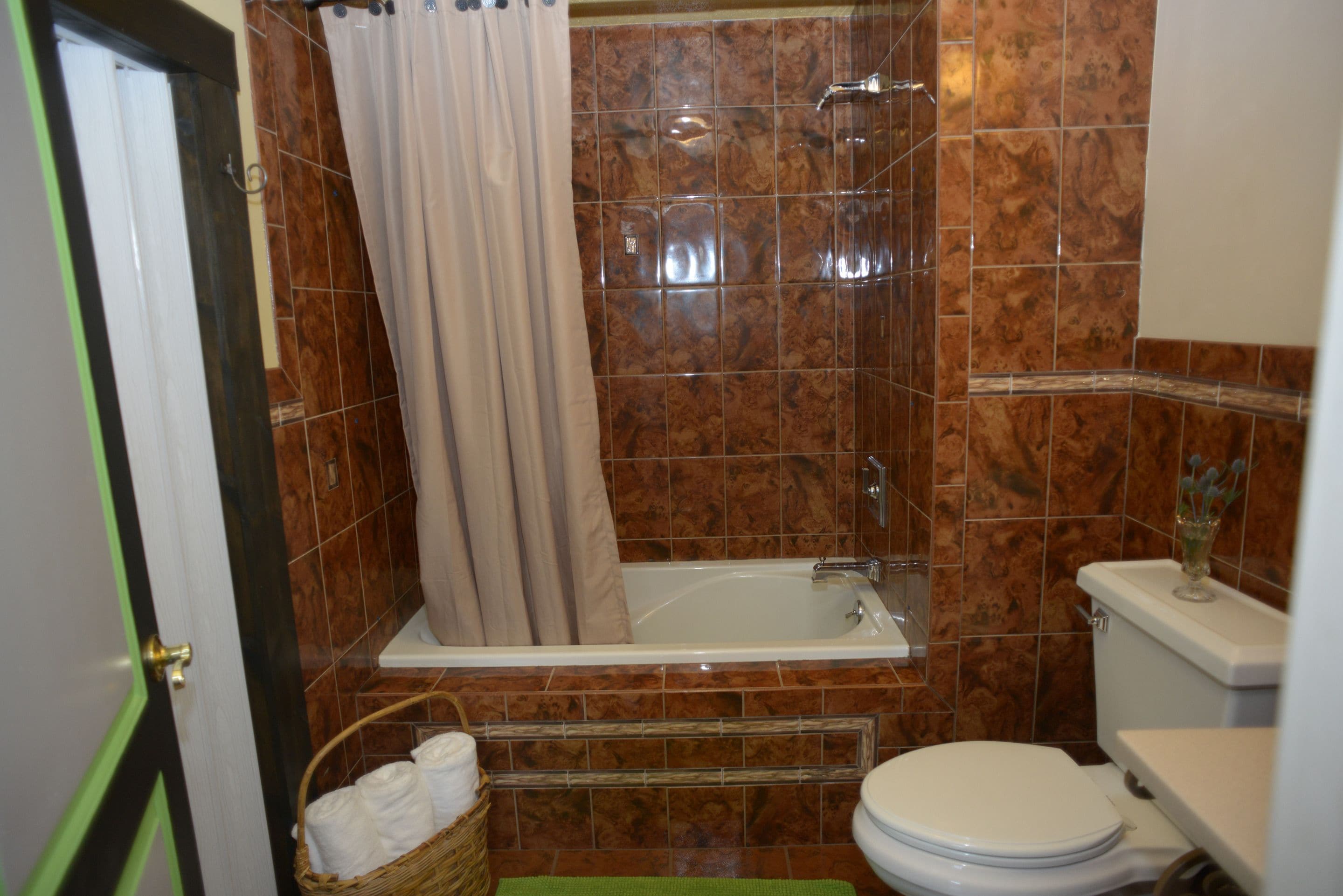Een badkamer met een bad, toilet en douchegordijn.