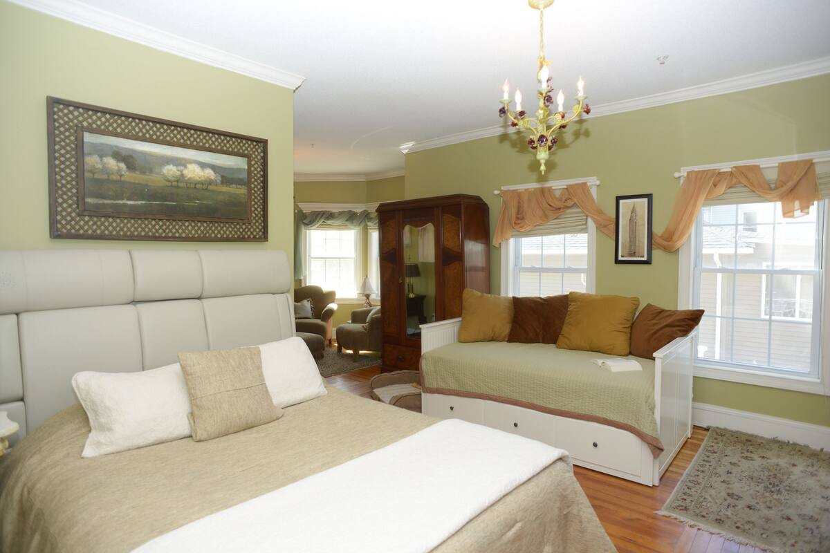 A bedroom with two beds, a chandelier, and a painting on the wall.