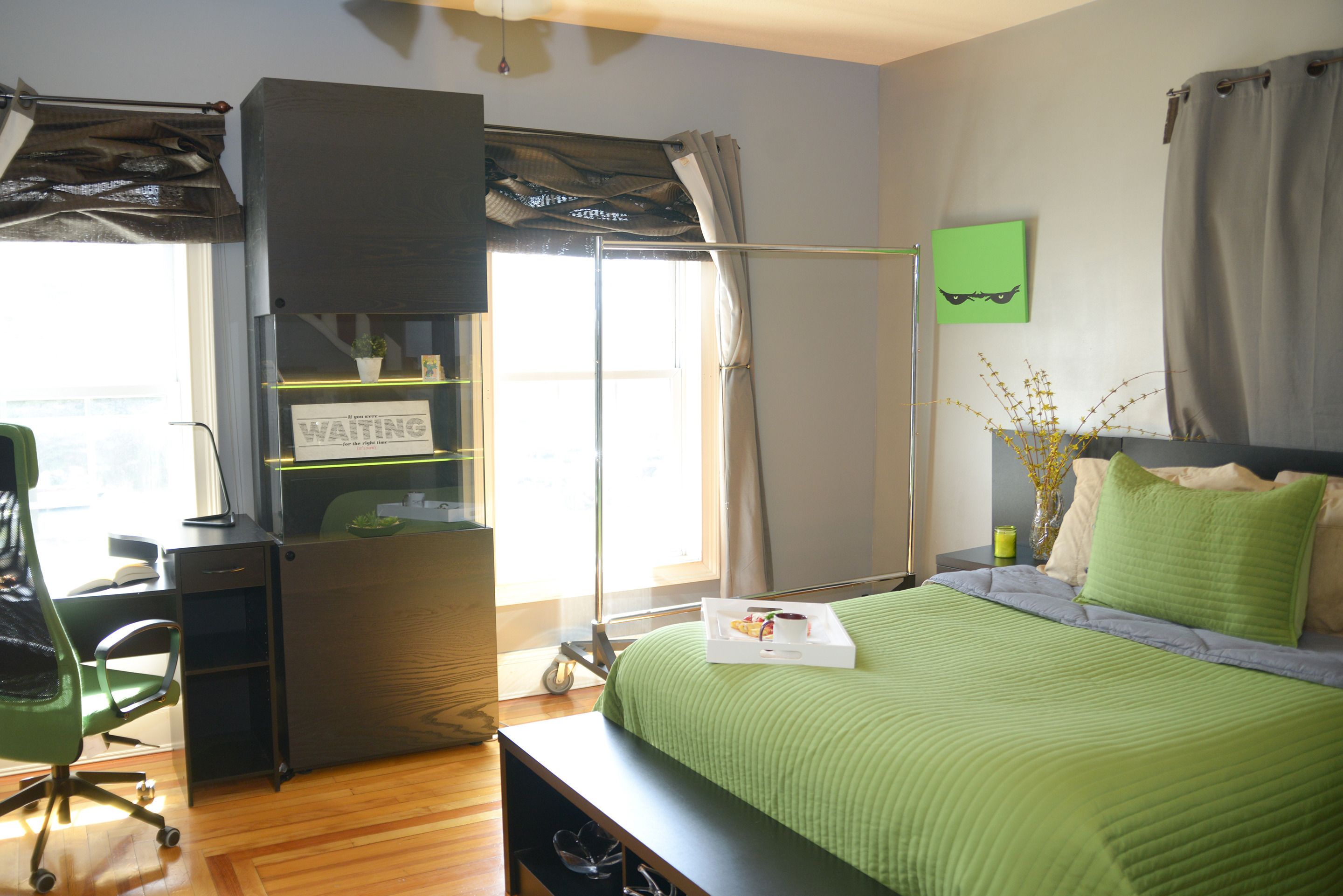 A bedroom with a bed, a desk, a chair, and a window with curtains.