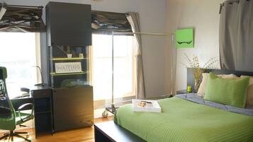 A bedroom with a bed, a desk, a chair, and a window with curtains.