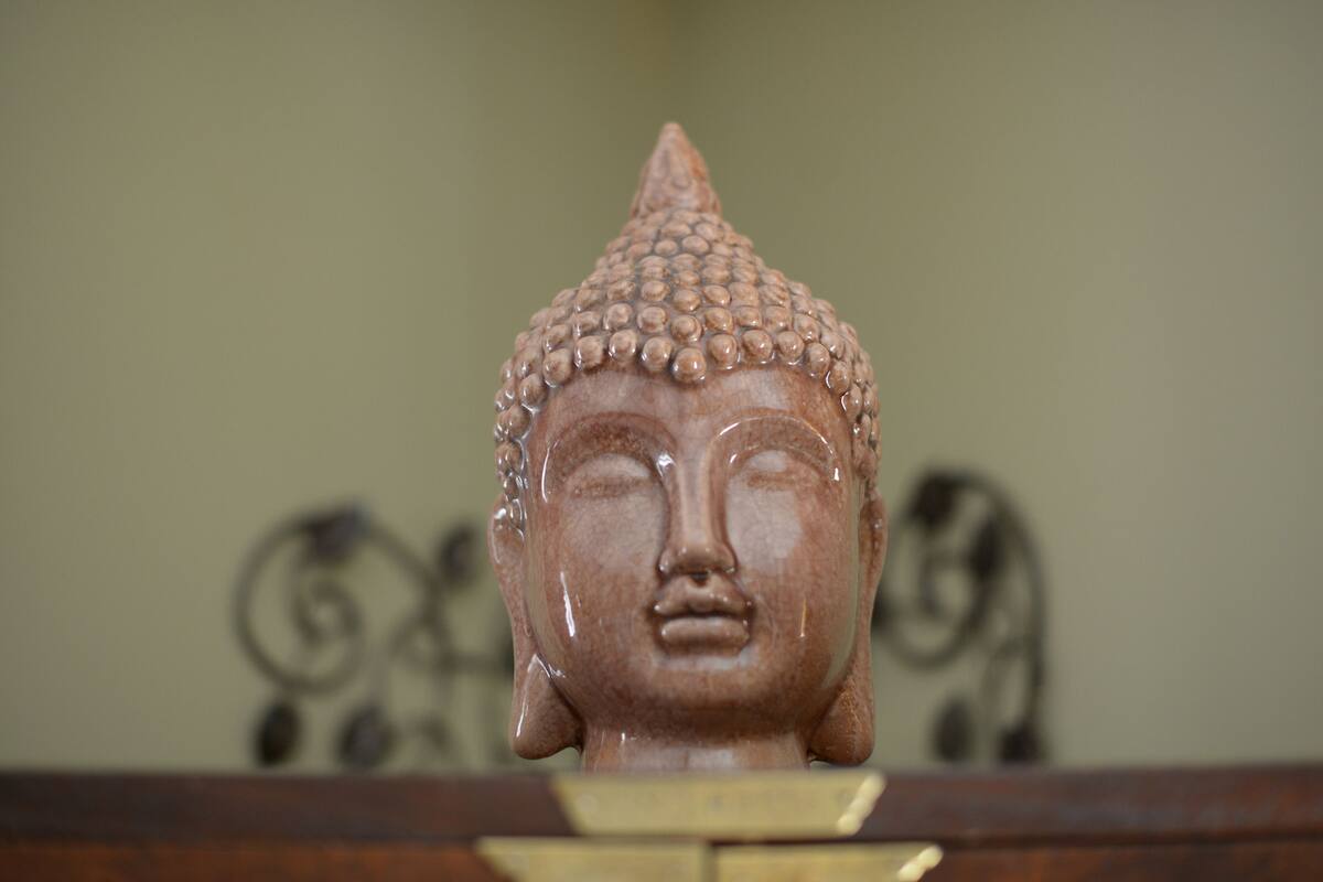A Buddha statue with a rounded head and a pointed top, placed on a wooden base.