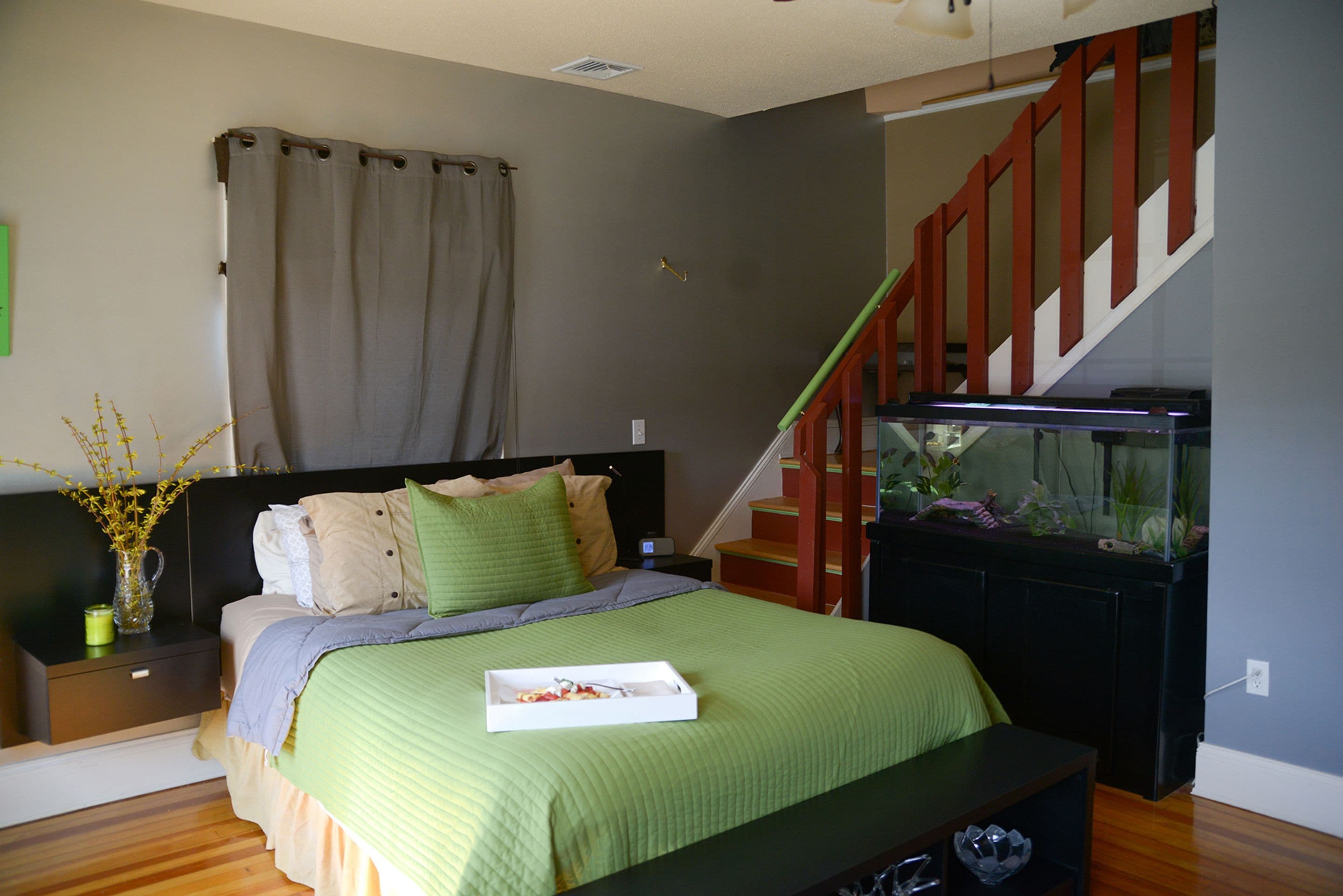 A bedroom with a bed, nightstand, dresser, and a staircase leading to an upper level.