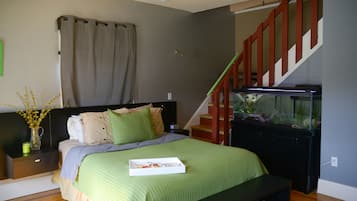 A bedroom with a bed, nightstand, dresser, and a staircase leading to an upper level.