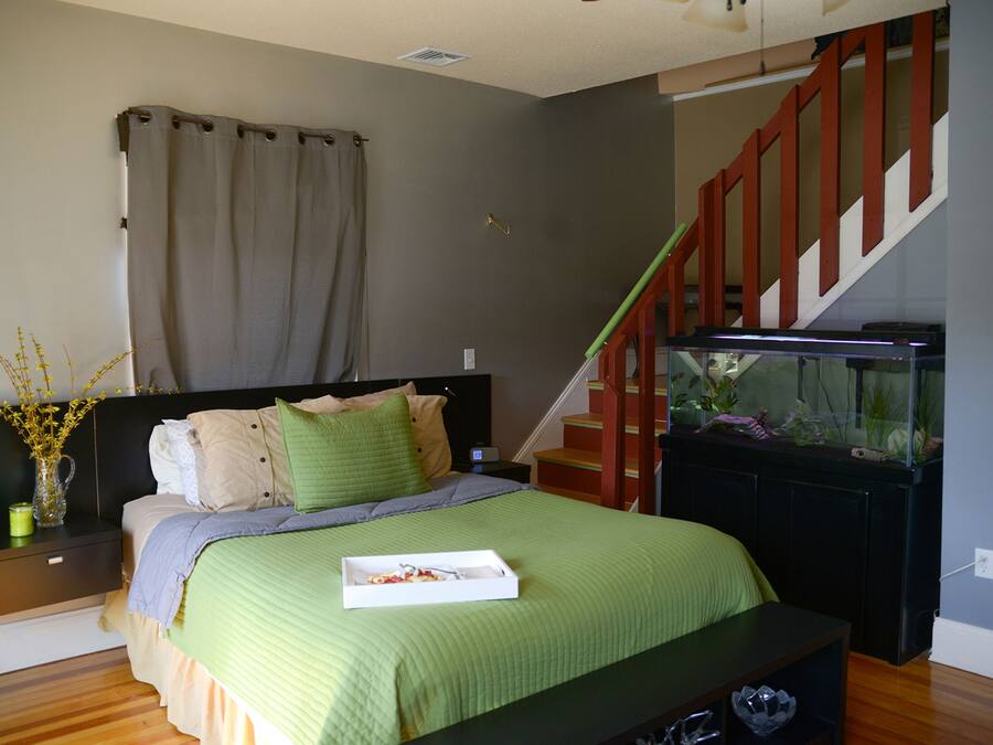 A bedroom with a bed, nightstand, dresser, and a staircase leading to an upper level.