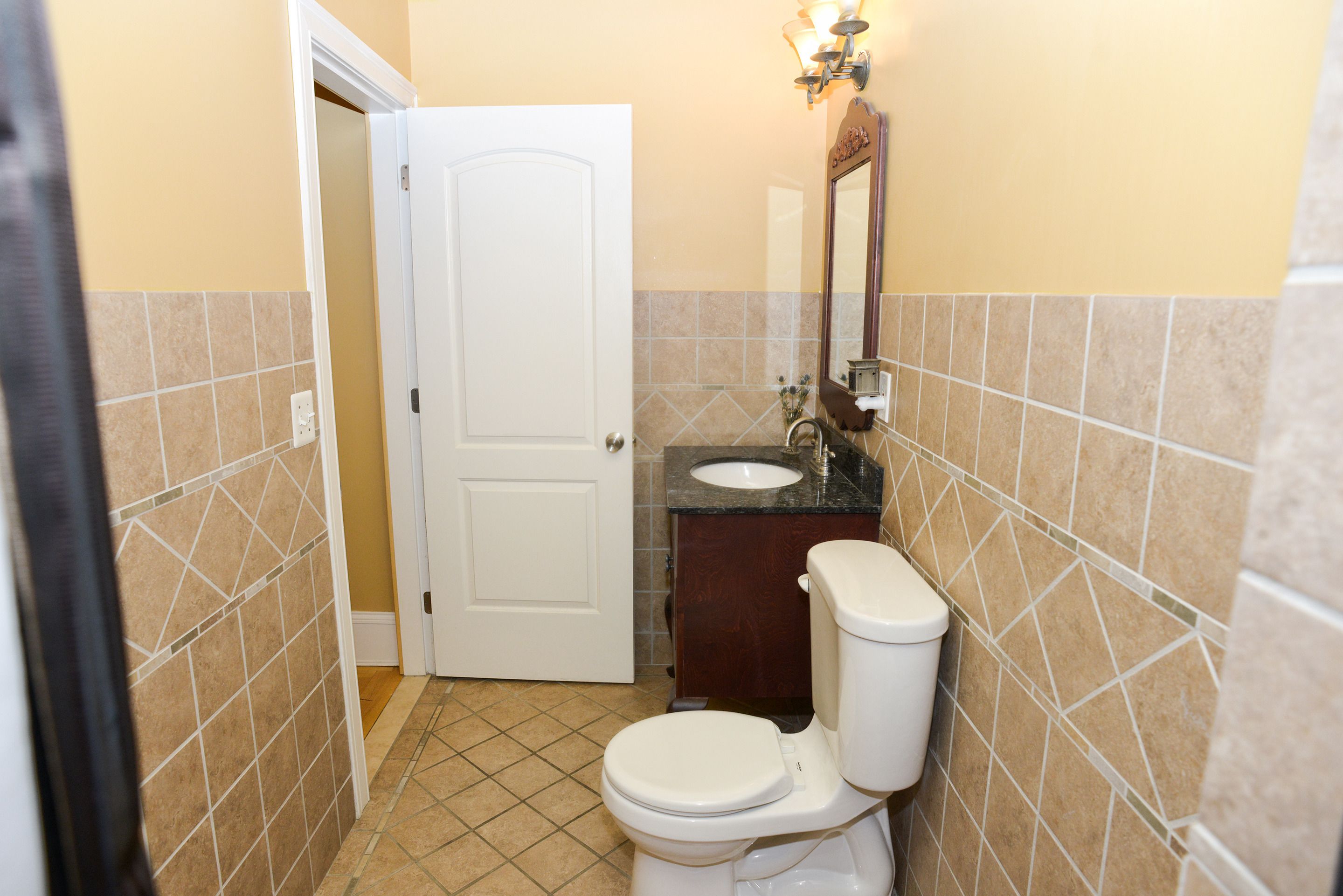 A small bathroom with a toilet, sink, and mirror.