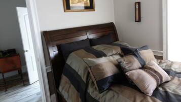 Een slaapkamer met een houten hoofdbord, een bed met gestreept beddengoed, een ingelijste wereldkaart aan de wand en een klein houten nachtkastje.