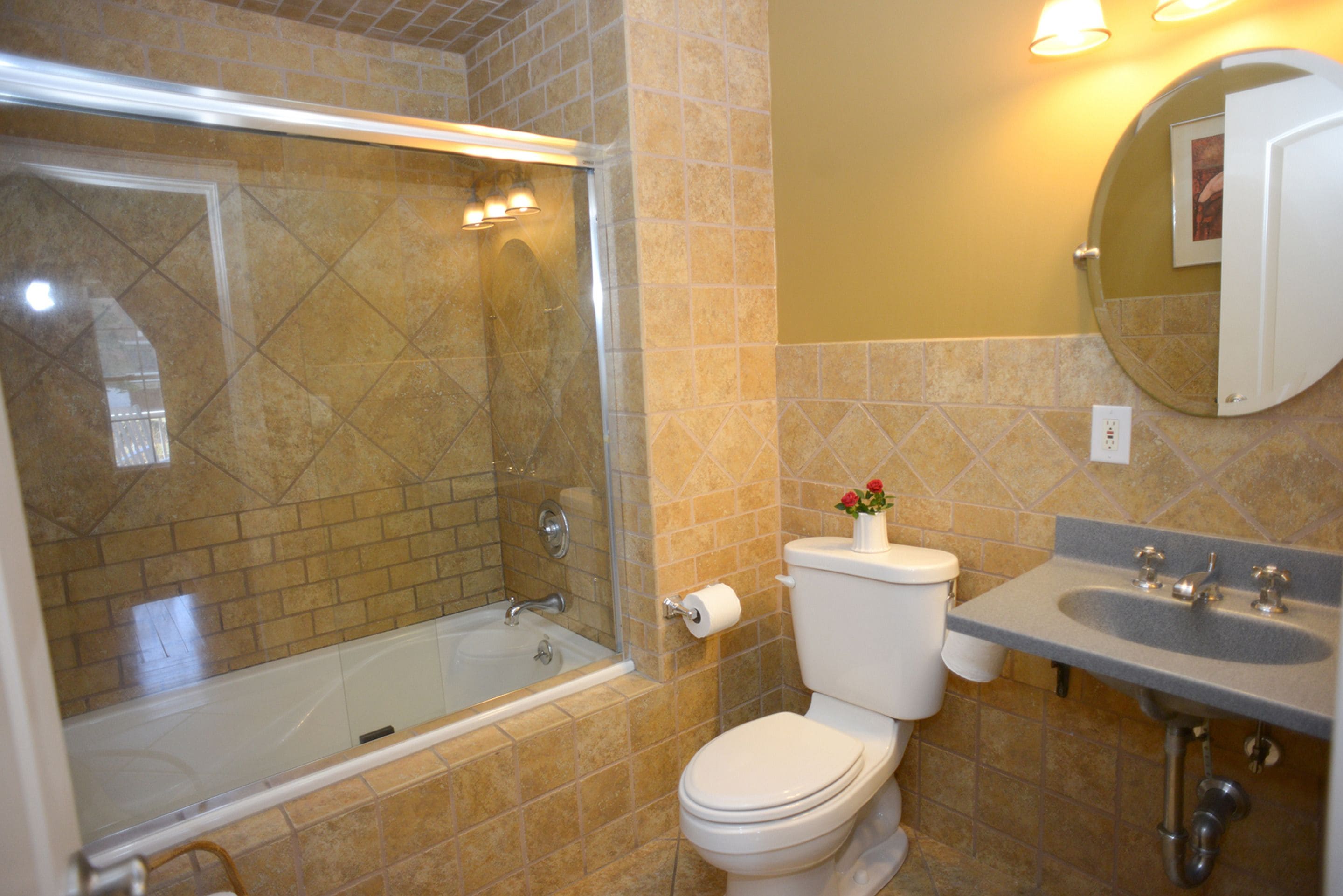 A bathroom with a bathtub, toilet, sink, and a mirror.