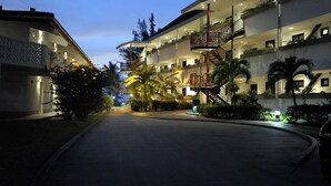 Ein mehrstöckiges Hotel mit Balkonen, einer gebogenen Auffahrt und gut beleuchteten Außenbereichen.