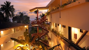 Ein Hotel mit einer Treppe, die zu einem Balkon führt, umgeben von üppiger Vegetation und Palmen.