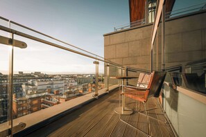 A balcony with a view of the cityscape, a wooden chair, and a glass railing. - Radisson Blu Royal Hotel, Dublin (Dublin)