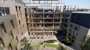 A multi-story building with a courtyard featuring outdoor seating and greenery. - Radisson Blu Royal Hotel, Dublin (Dublin)