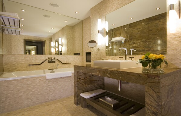 A modern bathroom with a large mirror, dual sinks, and a built-in bench.