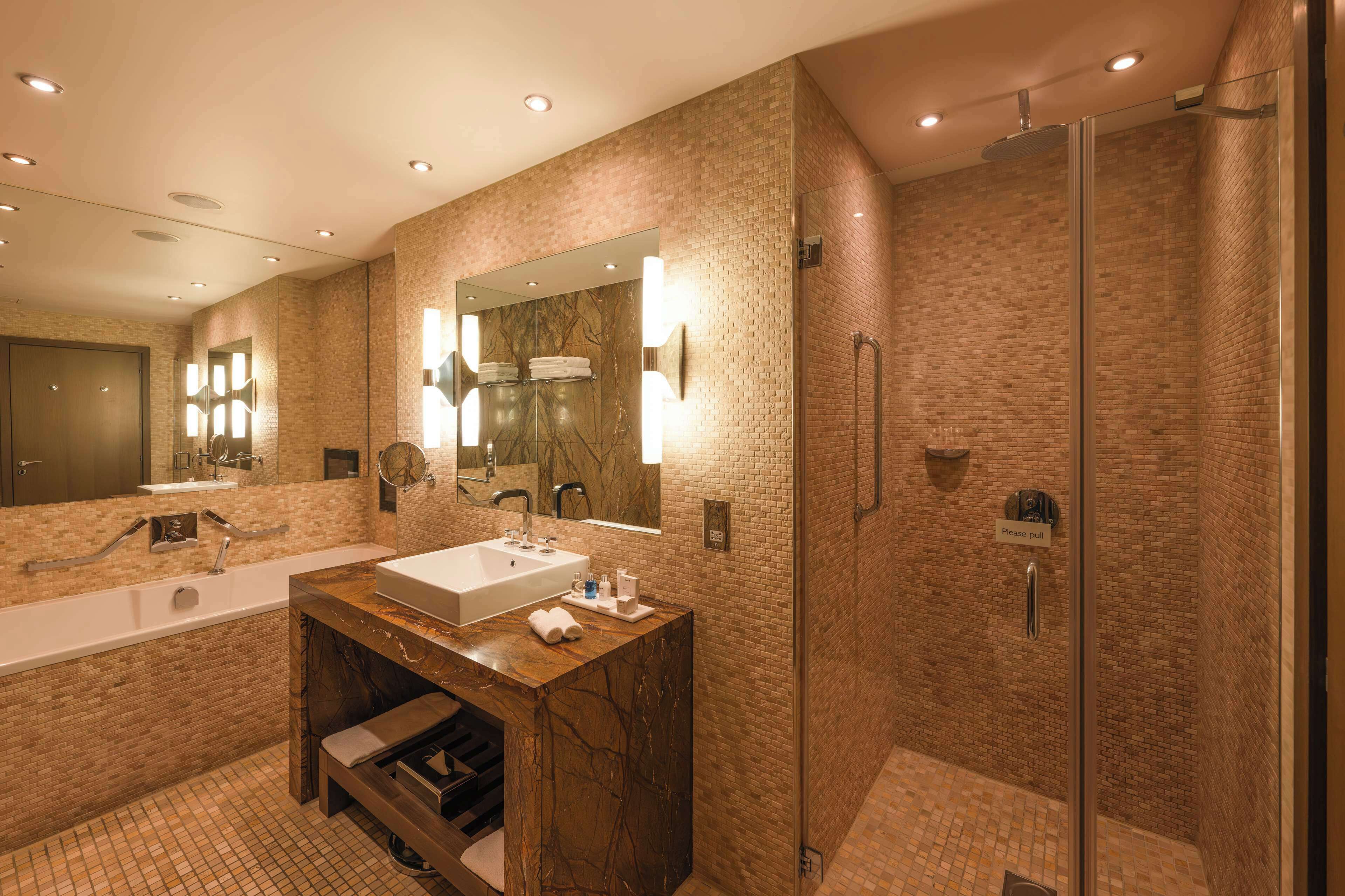 A modern bathroom with a large mirror, a sink, and a shower area.