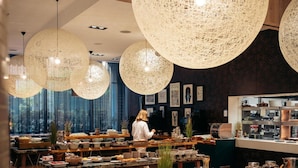 A restaurant with wooden flooring, large hanging light fixtures, and a counter with various food items and drinks. - Radisson Blu Royal Hotel, Dublin (Dublin)