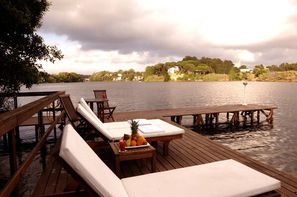 A wooden deck with lounge chairs and a table with fruit and a drink.