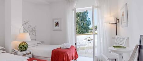 Habitación de hotel con dos camas, un escritorio con computadora, una silla, una mesa con lámpara y vistas al exterior.
