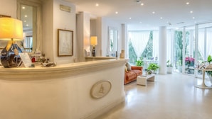 A reception area with a marble counter, a sofa, and a coffee table. - Il San Francesco Charming Hotel (Sabaudia)