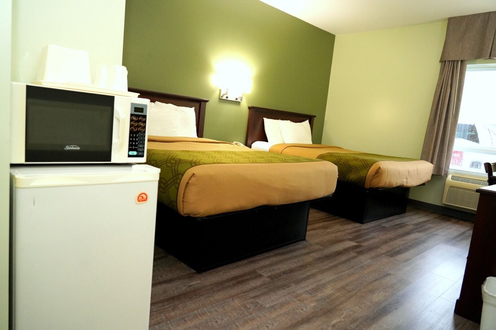 A hotel room with two beds, a microwave, and a refrigerator.